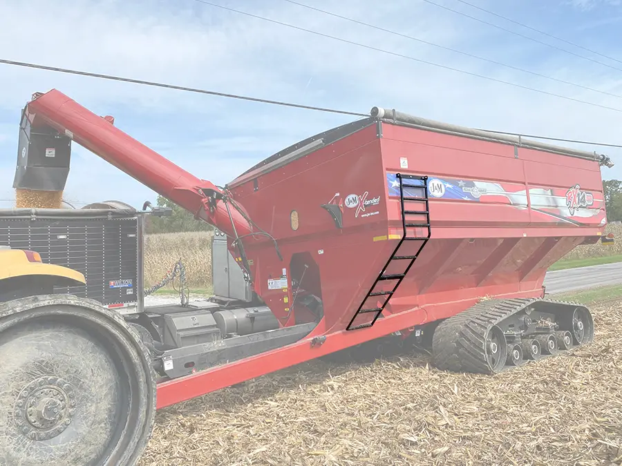 a red grain cart that is muted showing the side mounted ladder that provides safe access to the top of the grain cart