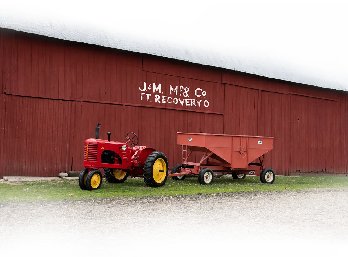 an old style gravity wagon that was one of the originals at J&M sitting in front of an old barn